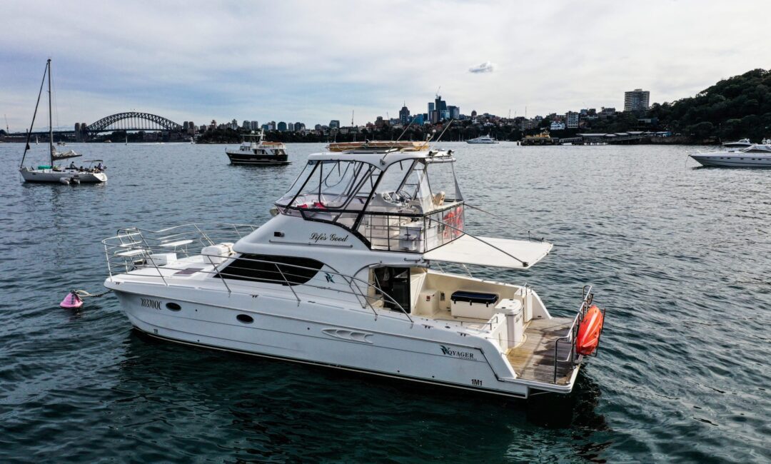 A private yacht charter named "Life's Good" floats on water with a cityscape and the Sydney Harbour Bridge in the background.